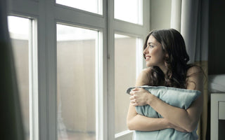 Nachdenkliche Person am Fenster – Stress und Haut