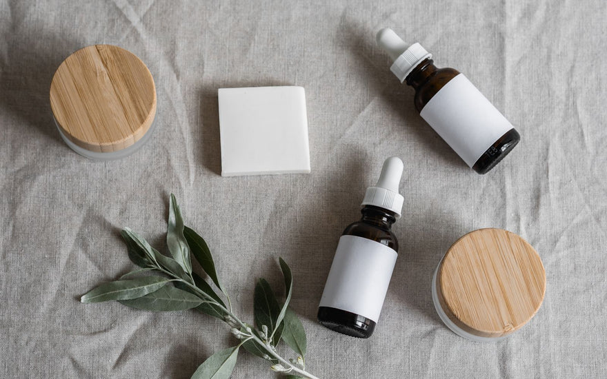 Serum-Fläschchen mit Pipette und Cremetiegel auf grauem Leinen – die typische Darreichungsform für Hyaluronsäure